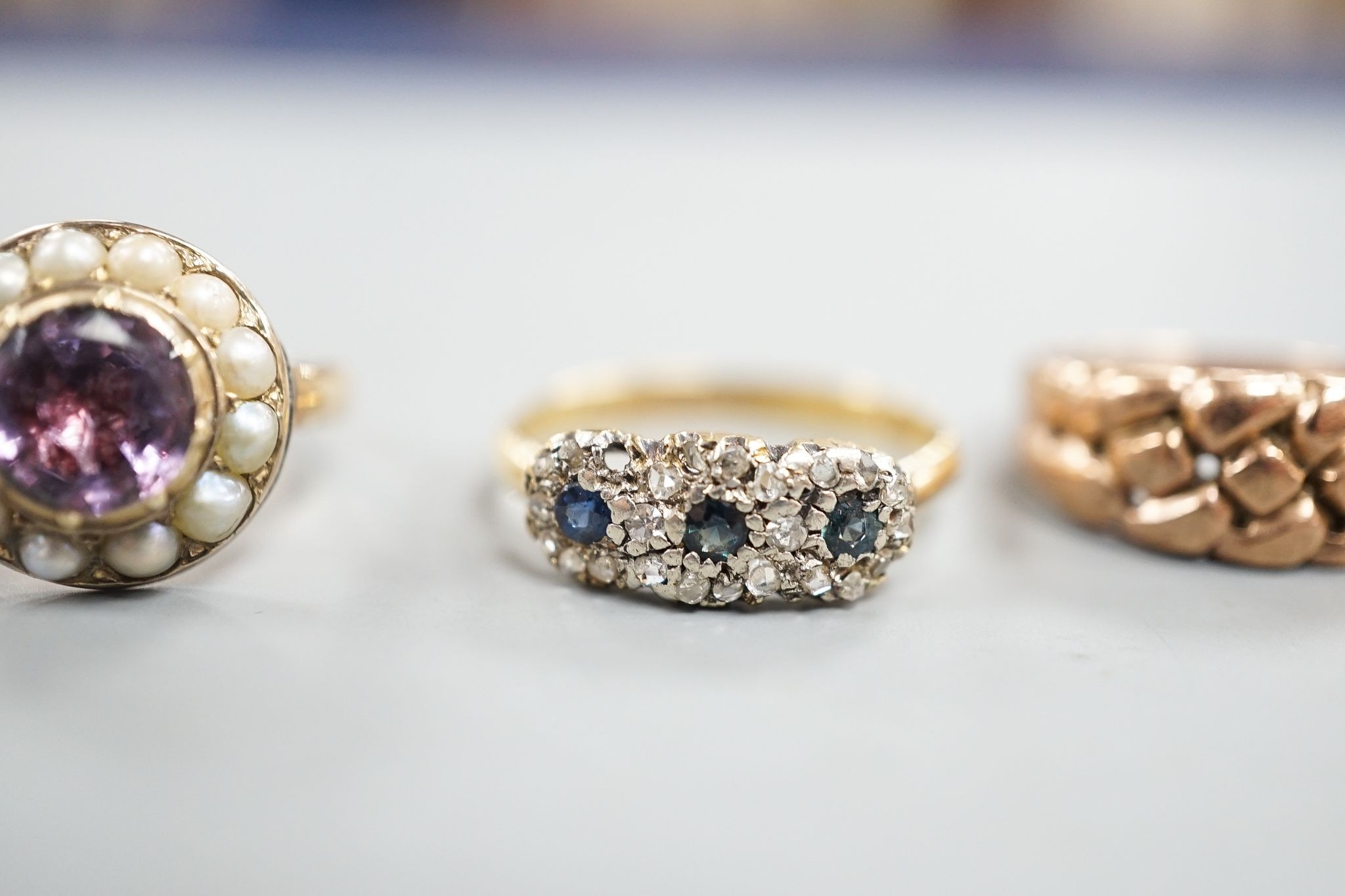 An early 20th century 18ct gold and gypsy set three stone coral ring, size P/Q, a similar sapphire and diamond set triple cluster ring, 5.5 grams, two similar 9ct gold rings, 7.7 grams and a yellow meta, foil backed amet